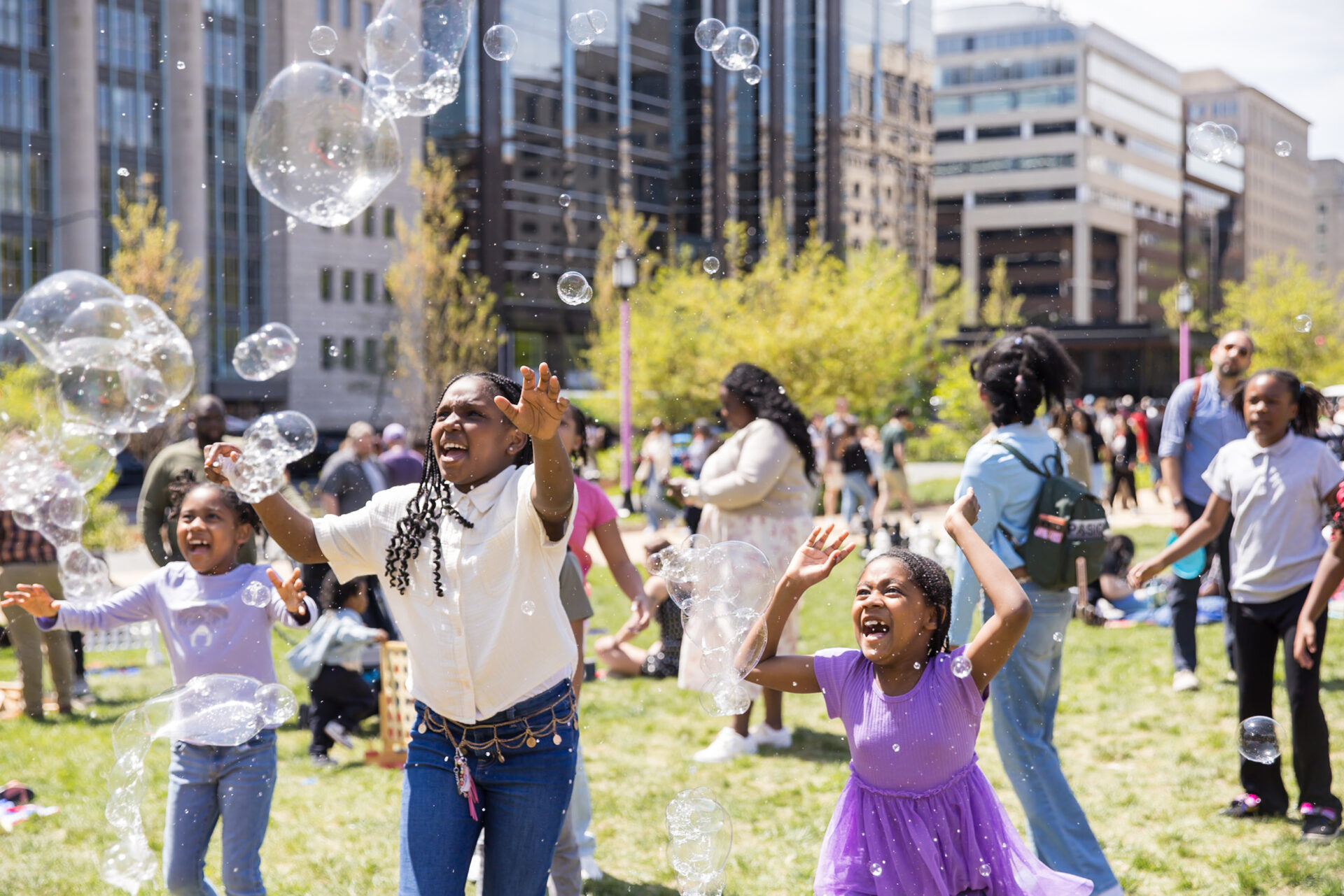 Kids happily playing with bubbles under sunny sky.
